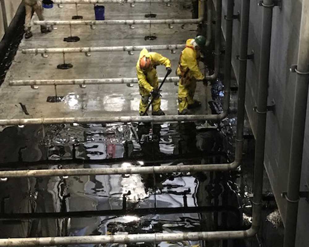 workers in yellow suits applying coating to floor